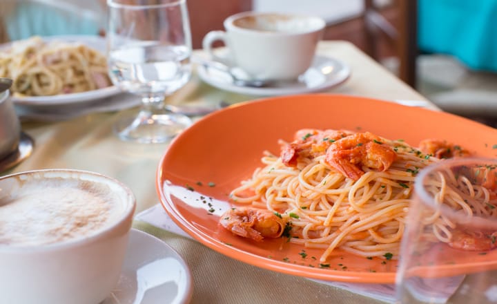 un plato de pasta italiana con un café sobre una mesa